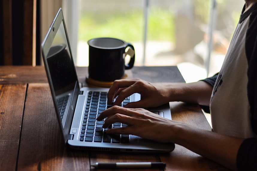 Young person sitting in the morning by their laptop drinking tea and writing in their blog