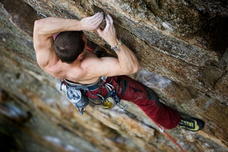 An adult man climbing a rock face alone