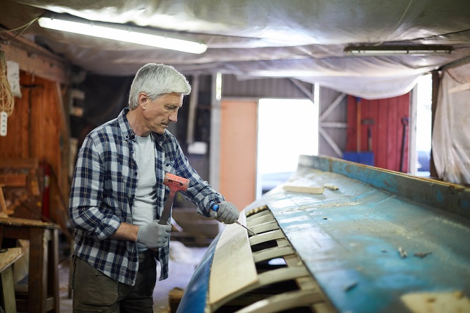 A middle aged man peeling the hull off the ship