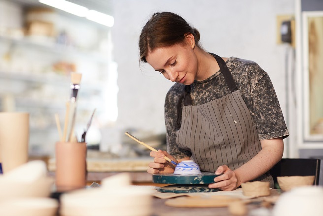 A young lady painting a cup very well